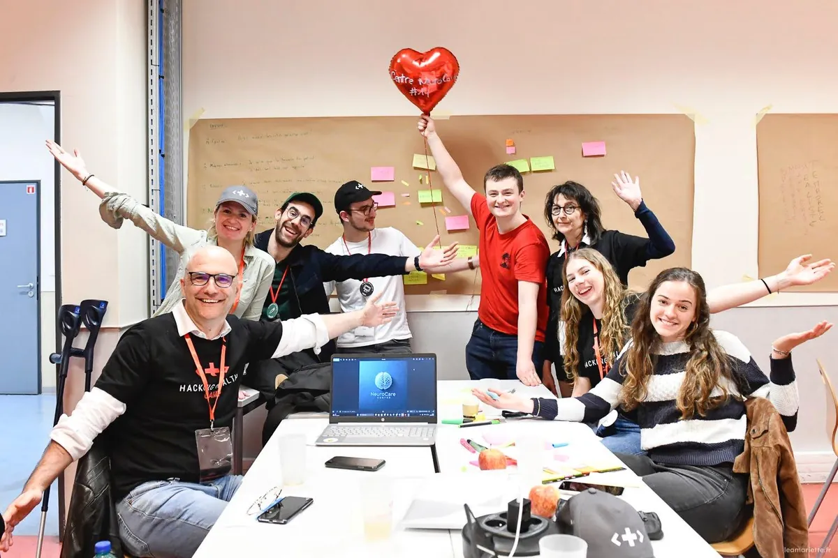 L’équipe NeuroCare au Hacking Health Camp 2025, bras ouverts autour d’un ballon en forme de cœur